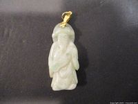 Front view of vintage jade pendant showing detailed carved figure and gold-toned bail.