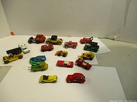 Wide shot showing the full lot of 16 vintage diecast toy vehicles from Matchbox and Corgi made in England in mixed colors and styles including cars and construction vehicles.