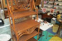 Photo showing the full wicker display shelf with three tiers and a decorative woven backrest.