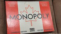 Box with red and white design featuring a large maple leaf and the text Monopoly Canadian Edition by Parker Brothers.