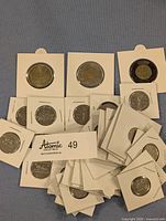 Group of Canadian commemorative coins including Klondike Loonie, D-Day Toonie, Black Ring Toonie, nickels, and several dimes all mounted in white cardboard coin holders.