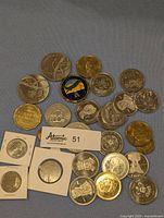 Photo showing a diverse array of commemorative and currency coins with some in protective holders, various themes and metal finishes visible.