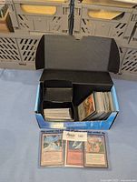 Open deck box showing stacked unsleeved Magic cards and a few sleeved cards laid out in front