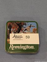 Tin with Atomic Collectibles label on top showing hunting scene with pheasant.