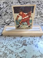 Front view of 1953 Parkhurst Glen Skov vintage hockey card propped upright against a wooden holder, showing player in red hockey uniform on ice with printed signature at bottom.
