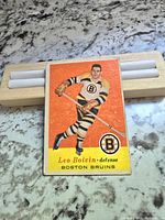 Front of the 1957 Topps Leo Boivin hockey card showing player in Bruins uniform with orange background and team logo.