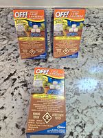 Three boxes of OFF Mosquito Lamp refills placed on a granite countertop. Two boxes sealed, one opened with partial contents.