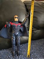 Front view of the 12-inch Robin action figure standing upright next to a measuring tape showing approx 12 inches tall.