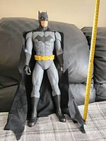 20-inch Batman action figure standing on a fabric surface with a measuring tape showing height.