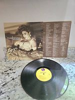 Photo of vinyl record cover sleeve with sepia image of Madonna and inner sleeve with song lyrics.