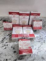 Seven boxes of Holiday Time LED mini and micro lights arranged on a countertop, showing packaging with product details.
