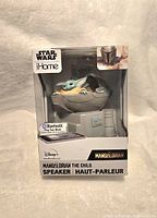 Front view of the sealed retail box showing The Child sitting in his pod, Star Wars and iHome branding, and Bluetooth logo.