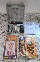 Cordless rotary tool with accessories and Halloween decorations laid out on counter.