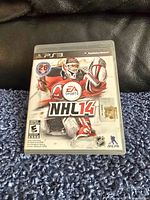 PlayStation 3 NHL 14 video game case cover showing front artwork with goalie and EA Sports logo.