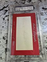 Front image of red memorial card with Bernie Snyder autograph mounted and encased in PSA/DNA graded slab.