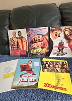 Full-color movie press release posters for Bowfinger, Bio-Dome, Big Fat Liar, Brain Candy, Nacho Libre, and 200 Cigarettes arranged on couch