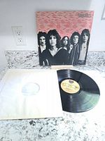 Front cover of Sparks vinyl record album featuring band members and background red text.