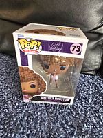 Photo of Whitney Houston Funko Pop figure in original box, number 73 from Pop! Icons series, showing figure with brown curly hair and pink dress.