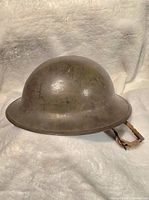 Side view of Canadian MK-2 Brodie helmet with olive drab finish showing wear and original strap attached.
