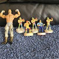 Loose 7 inch Eddie Guerrero WWE action figure posed flexing muscles with four WWF wrestler self ink stamps in front on carpet background