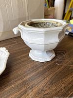 White ironstone china planter, octagonal shape with two decorative handles and flower frog insert inside. Placed on a wooden surface.