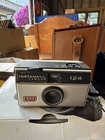 Kodak Instamatic 124 camera with black and white body, front view showing lens and Kodak logo.