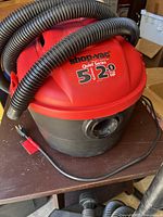 Photo of a red and black Shop-Vac Quiet Series 5 gallon 2.0 HP wet/dry vacuum with hose featured.