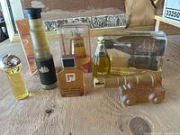 Full view of all 8 vintage perfume bottles on wooden surface, showing various shapes such as cannon, ship, and architectural forms.
