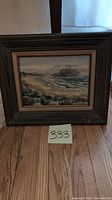Full view of framed watercolor painting showing coastal scene with Morro Rock, wooden frame and number 333 in front.