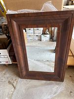 Front view of the brown wooden mirror frame showing traditional polished wood grain finish.