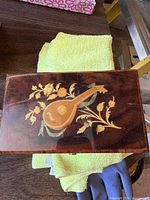Top view of the wooden music box showing floral and lute inlay design on dark polished wood lid.