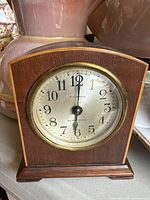 Front view of Seth Thomas small wooden mantle clock showing dial, numerals, and brass rim.