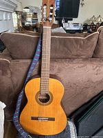 Full view of Continental DC 310 acoustic guitar with strap attached, showing natural wood finish and classical body shape.