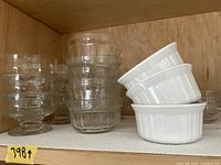 Stack of assorted clear glass dessert and small bowls with 3 white ceramic ramekins