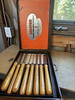 Seven wood turning chisels in wooden box with orange branded lid