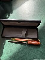 Open case displaying the ballpoint pen with brown marbled finish and gold-tone clip and tip.