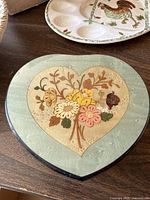 Closed heart-shaped jewelry box showing floral inlay on the lid in a heart shape with green outer border.