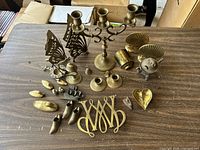 Full overview of the brass decorative collection spread on a table showing all items including candle holders, figurines, paper weights, and decorative dishes.