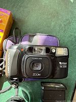 Front view of Discovery Fuji Auto Focus 190 Zoom 35mm camera showing Fujinon lens and built-in flash with camera carrying strap and green background.