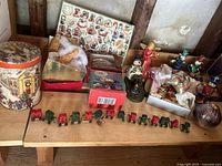 Assorted Christmas ornaments and figurines including angels, toy soldiers, glass and wooden ornaments, and wooden toy train string on wooden surface.