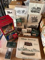 All boxed and unboxed Heritage Village Collection Christmas village pieces including buildings, train set, and figurine sets arranged together