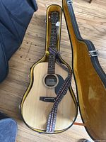 Guitar laid open in hard shell case with strap visible