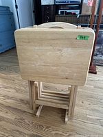 Front view of the stacked natural wood folding TV tray tables with visible wood grain and foldable legs.