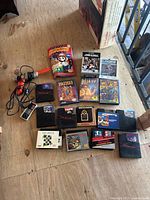 Photo showing the game cartridges with some in original Nintendo sleeves and boxes, two controllers including a standard NES controller and Zapper light gun.
