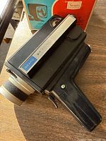 Side view of the Sears Super 8 film camera showing the pistol grip, zoom lever labeled 'Sears 21x Zoom,' and part of the camera body with visible wear.