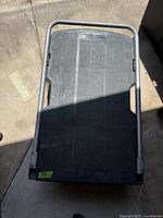 Top view of Rubbermaid black plastic utility cart platform and handlebar.