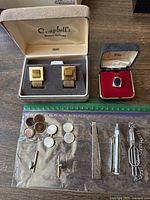 Wide shot of all items including tie clips, cufflinks, shirt studs, and ring, alongside a ruler for scale.