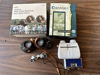 All four binoculars and their original boxes or cases displayed on a wood surface.