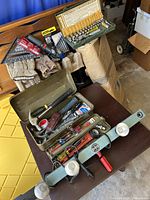 View of open green metal toolbox revealing assorted hand tools and accessories inside