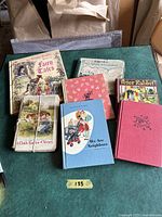 Photo of nine vintage children's books displayed on a green surface, showing front covers and various book sizes and styles.